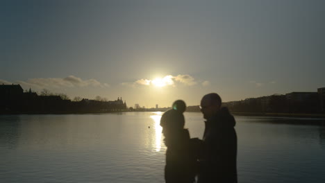 Sunset-over-the-river-in-Copenhagen,-Denmark,-tourists-walk-past