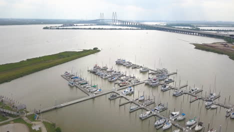 Aerial-view-over-a-boat-dock-overlooking-the-bay-and-a-cable-stayed-fridge-in-a-distance