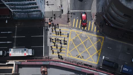 Menschen,-Die-Die-Gelbe-Fußgängerspur-An-Der-Kreuzung-In-Hongkong-überqueren,-Während-Die-Fahrzeuge-Auf-Der-Fahrspur-Stehen,-Haben-Angehalten-–-Luftaufnahme