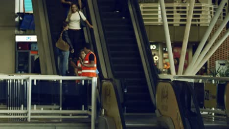 Airport-workers-and-travelers-riding-escalator-inside-airport,-super-slow-motion