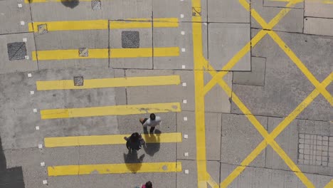 Gente-Cruzando-El-Paso-De-Peatones-Amarillo-En-Hong-Kong---Vista-Superior