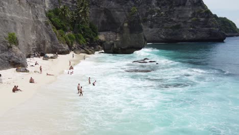 Aerial,-People-relaxing,-sunbathing-and-swimming-at-Diamond-Beach-in-Nusa-Penida-Island,-Bali---Indonesia