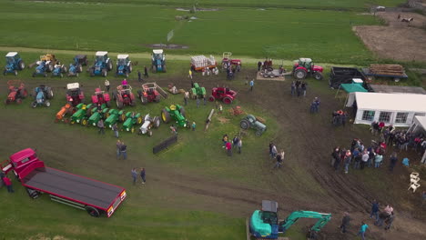 Aerial-view-of-a-tractor-meet-up-in-Wilsveen,-the-Netherlands,-panning-right-to-left-over-green-fields-with-people-walking-around