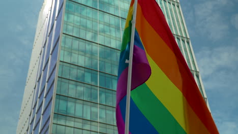 LGBTQ-symbolic-flag-Being-Waved-During-Freedom-March-In-Warsaw,-Poland-Against-Office-Block-Building
