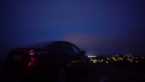 Auto-Parkte-Auf-Einem-Hügel-Mit-Blick-Auf-Die-Stadt-Bei-Nacht