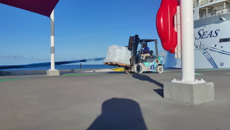 A-robust-forklift-truck-expertly-transports-hefty-ice-bags-across-a-pier,-ensuring-a-constant-supply-of-cooling-refreshment-on-the-island