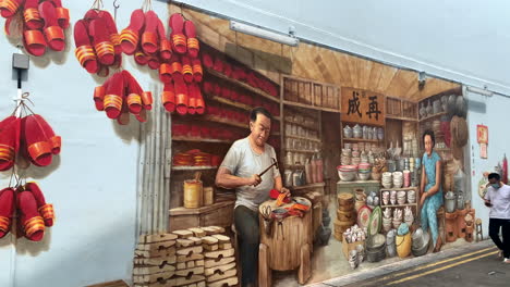 Ein-Wandgemälde-Eines-Chinesischen-Paares-An-Der-Wand-In-Chinatown,-Singapur,-Mit-Einem-Vorbeikommenden-Mann-Mit-Gesichtsmaske