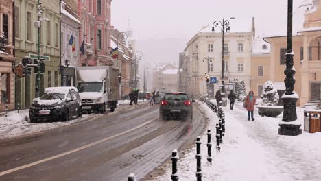 Menschen-Und-Fahrzeuge-Fahren-In-Der-Stadt-Brasov-Während-Winterlicher-Regenschauer-In-Rumänien,-Siebenbürgen