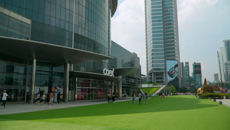 People-Entering-Coex-Shopping-Mall-On-A-Daytime-With-ASEM-Tower-In-Distance-At-Gangnam-District-In-Seoul,-South-Korea