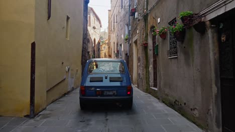 Car-Driving-On-Narrow-Cobbled-Street-Through-Houses-In-Pitigliano,-Italy