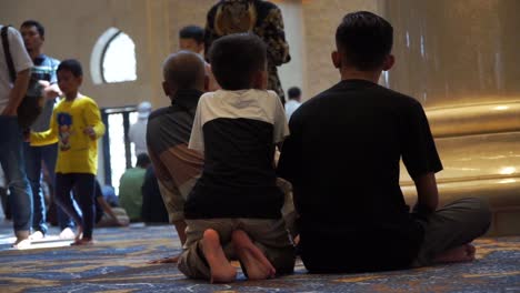 Father-and-the-son-sit-on-the-mosque-in-Sheikh-Zayed-Grand-Mosque,-Surakarta,-Central-Java,-Indonesia