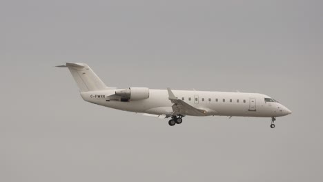 Kamerafahrt-Eines-Weißen-Flugzeugs-Mit-Der-Hecknummer-C-fwrr-Mitten-Im-Flug-Mit-Grauen-Wolken-Im-Hintergrund