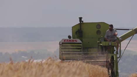 Slow-motion-shot-of-a-harvest-combine-harvesting-wheat-in-a-ripe-wheat-field-on-a-hot-summer-day
