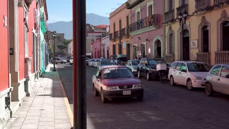 Calles-De-La-Ciudad-Con-Un-Taxi-Rojo-Y-Blanco-Pasando-Con-Señalización-De-Destino,-Tiro-A-La-Derecha