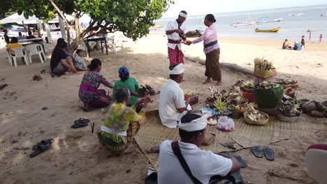 Balinesische-Hindu-Familie-Führt-Ein-Religiöses-Ritual-Am-Strand-Von-Sanur,-Bali,-Indonesien,-Mit-Traditioneller-Kleidung-Und-Opfergaben-Durch