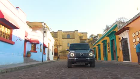 Aerial-low-angle-view-of-G-class-Mercedes-Benz-driving-through-colorful-street-in-South-America