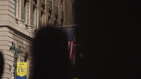 Aufschlussreiche-Aufnahme-Der-Amerikanischen-Flagge-Auf-Einem-Gebäude-In-New-York-City-An-Einem-Sonnigen-Tag---Zeitlupe