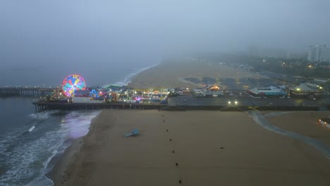 Aerial-view-toward-the-foggy-Santa-Monica-pier,-cloudy-day-in-Los-Angeles,-USA