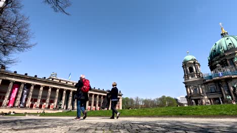 Couple-Walking-Past-The-Pleasure-Garden-In-Berlin-Towards-Altes-Museum-On-Nice-Day-With-Clear-Blue-Skies