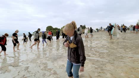 Crowds-of-barefoot-visitors-walk-carefully-on-slippy-wet-mineral-formations