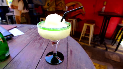 A-closeup-of-a-frozen-margarita-cocktail-on-a-table-with-a-drinking-straw