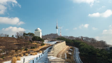 Zeitraffer-Von-Wolken,-Die-Sich-über-Den-Seoul-Tower-Und-Die-Stadtmauerbefestigung-Im-Winterlichen-Namsan-Park-Bewegen,-Heranzoomen