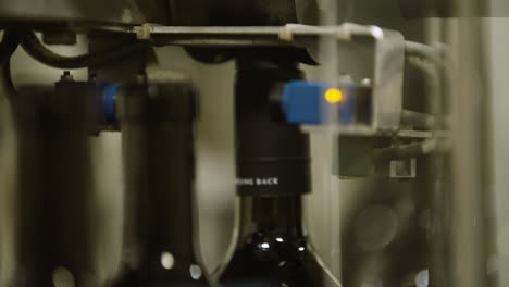 Conveyor-belt-of-wine-bottles-going-through-automated-labeling-process