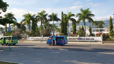 Scooters,-cars,-trucks-and-public-transport-microlet-buses-driving-past-Government-Palace-of-Timor-Leste-in-capital-city-of-Dil,-East-Timor