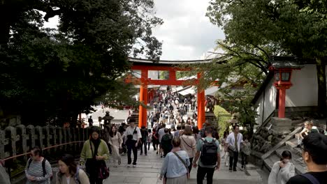 Belebte-Szene-Mit-Touristen,-Die-Treppen-Zum-Riesigen-Torii-Tor-Bei-Fushimi-Inari-Taisha-Hinuntergehen