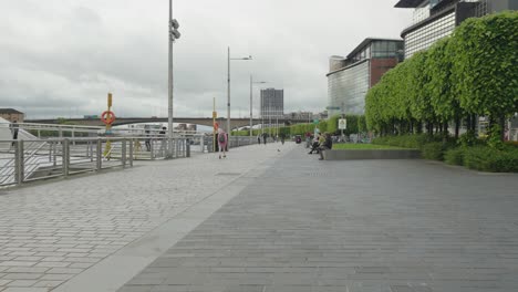 People-walking-and-cycling-past-the-River-Clyde-in-Glasgow-city-centre