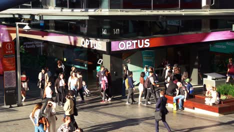 Tilt-down-view-of-the-Optus-flagship-store-along-Brisbane's-Queen-Street-mall,-crowded-with-students-and-pedestrians-in-the-center-of-the-plaza-at-central-business-district