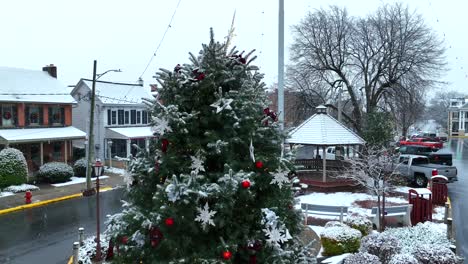 Christmas-tree-in-small-town-USA-square-covered-in-snow-during-snow-flurries