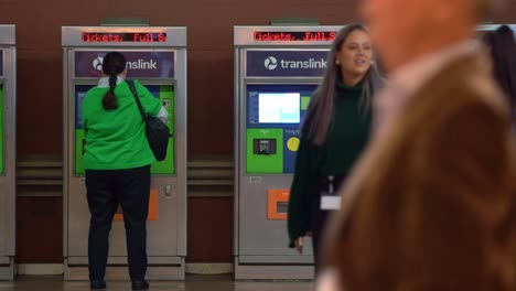 Off-work-peak-hours-at-Brisbane-city-central-station,-commuters-rushing-to-the-platform-and-traveller-buying-ticket-from-self-service-ticketing-machine-in-the-background,-static-shot