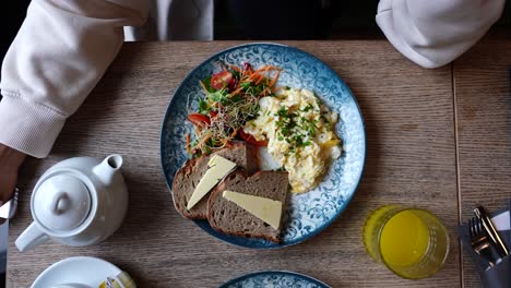 Zoom-out-of-vegetarian-restaurant-scrambled-egg,-salad-and-bread-dish-on-table