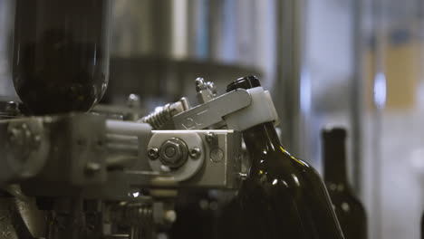Industrial-machine-arm-grabbing-empty-wine-bottles-to-be-washed-on-assembly-line