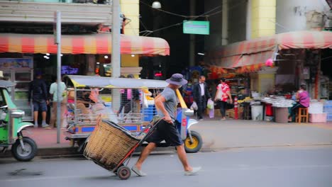 Hombre-Tirando-De-Una-Cesta-Vacía-En-Las-Calles-De-Bangkok-En-El-Mercado-De-Flores