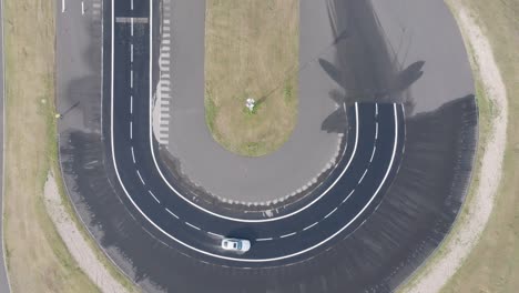 Aerial-top-down-view-of-car-drive-sharp-turn-on-weather-simulation-track