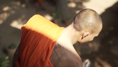 Behind-shot-of-a-buddhist-monk-performing-a-water-blessing-ritual-at-Angkor-Wat---Siem-Reap,-Cambodia