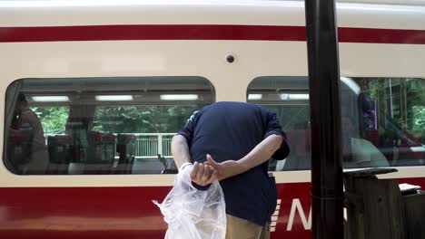 Elderly-Japanese-Man-Bowing-As-Train-Approaches-Gokurakubashi-Station-In-Koyasan