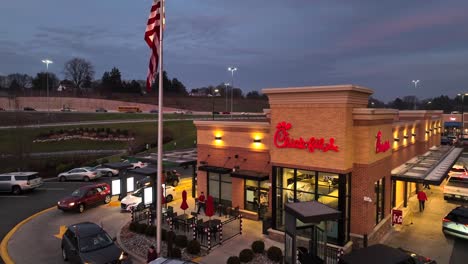 Busy-Chick-Fil-A-restaurant-and-drive-through-with-American-flag-during-sunset