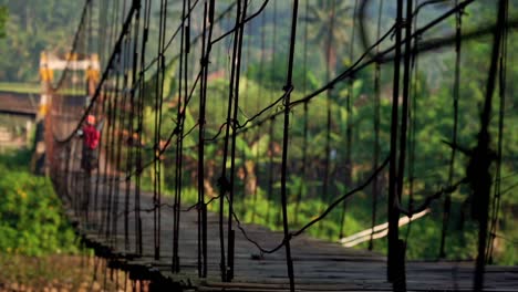 Eine-Traditionelle-Holzbrücke-über-Einen-Großen-Fluss,-An-Dem-Motorradfahrer-In-Der-Indonesischen-Landschaft-Vorbeifahren-–-Aufnahme-Aus-Niedrigem-Winkel