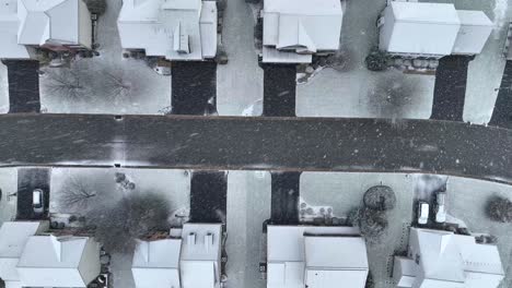 Top-down-aerial-rising-view-of-a-snow-dusted-street-and-houses-with-bare-trees