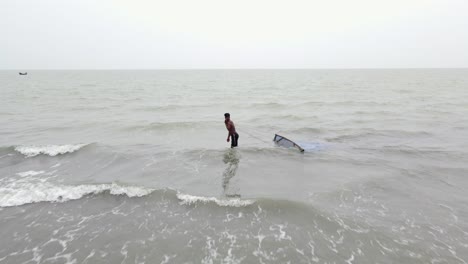 Fisherman-Dragging-Fishing-Net-Across-Sea-Waves-at-Kuakata-Sea-Beach,-Bangladesh