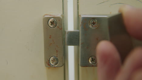 Slow-motion-close-up-of-hand-locking-bathroom-stall-door-and-then-moving-away
