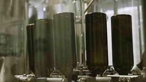 Empty-wine-bottles-being-washed-upside-down-on-factory-assembly-line