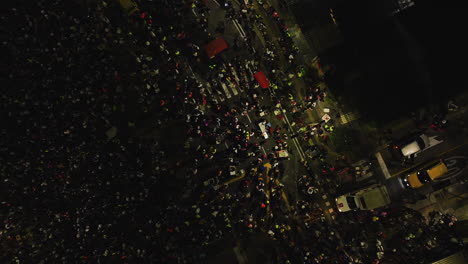 Aerial-view-of-a-ambulance-on-crowded-night-streets-of-Barranquilla,-at-Carnaval-Batalla-de-Flores,-in-Colombia