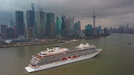 Viking-Sun-Cruise-Ship-Traveling-on-Huangpu-River-with-Skyline-in-Background-in-Shanghai,-China