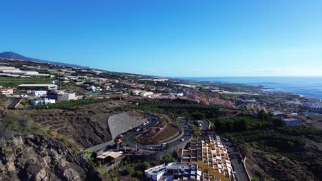 Aerial-Tenerife-Canary-Island-,-Los-Gigantes-sand-beach,-palm-trees-and-coastal-road