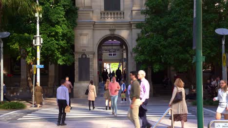 Cinematic-static-shot-of-pedestrians-and-office-workers-walking-across-Queen-street,-bus-and-car-traffic-with-heritage-listed-general-post-office-building-and-laneway-in-the-background