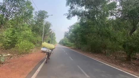 Ein-Mann-Mit-Gepäck,-Der-Auf-Einer-Indischen-Landstraße-In-Orissa-Radelt